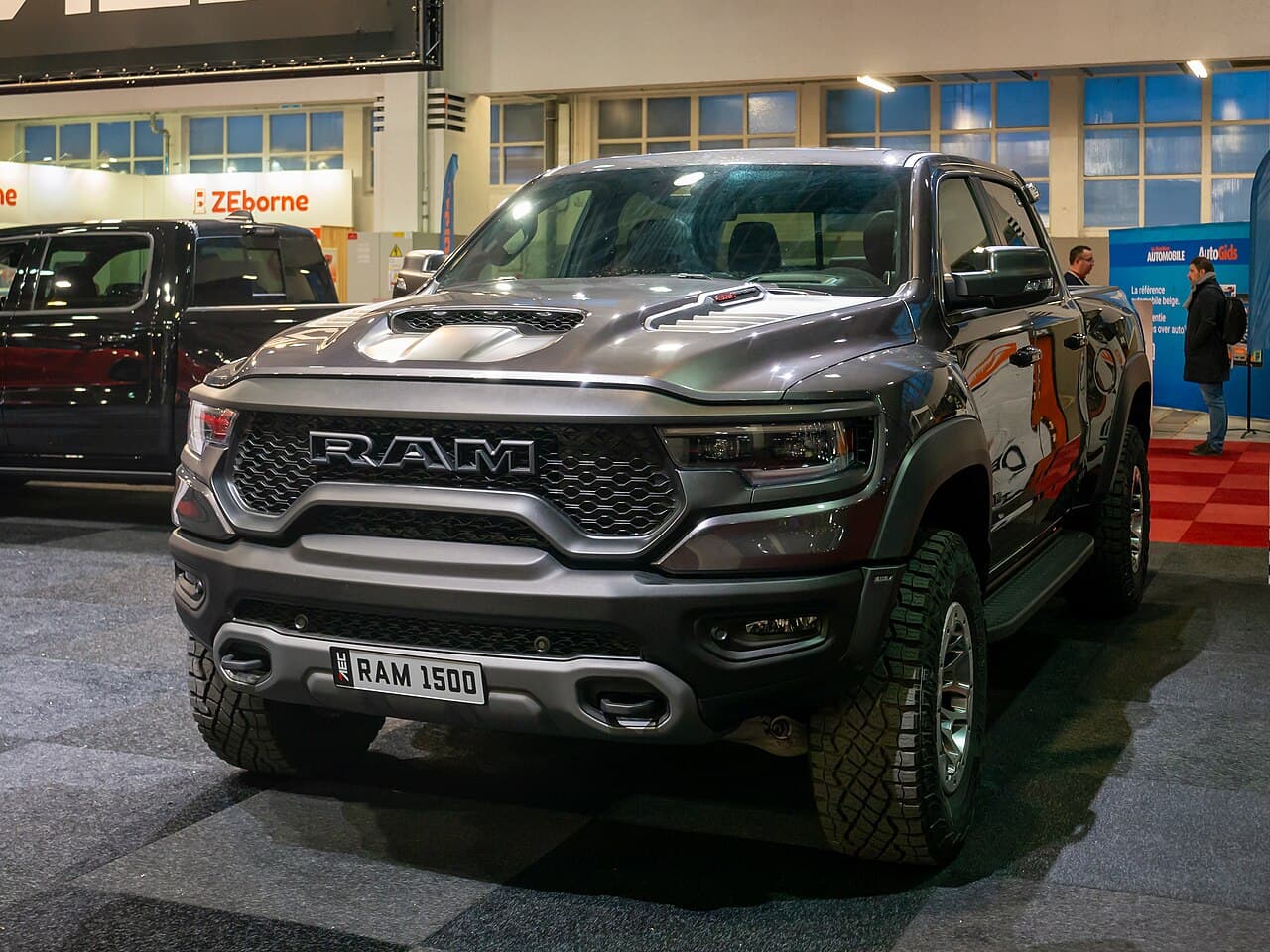 Front view of a gray Ram 1500 TRX at Brussels Auto Show 2024, indoors under show lighting.