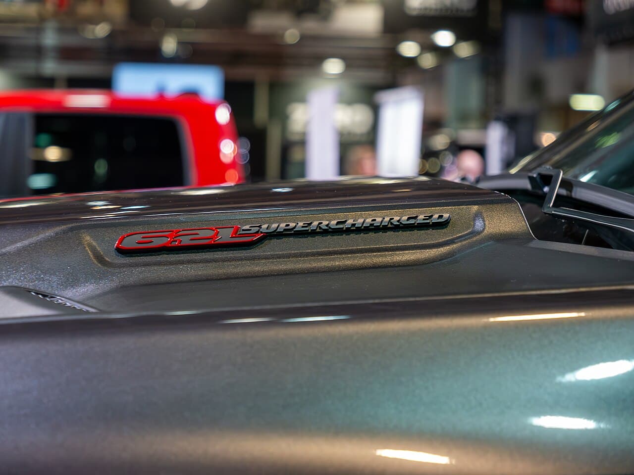 Close-up detail of the hood bulge and '6.2L SUPERCHARGED' badge on a Ram 1500 TRX at Brussels Auto Show 2024.