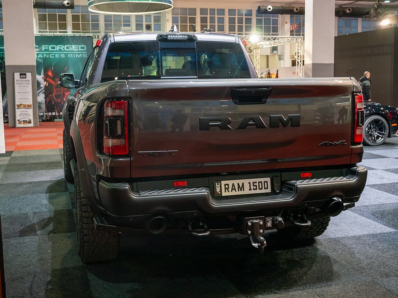 Rear view of a gray/maroon Ram 1500 TRX with visible 'TRX' and '4x4' badging on the tailgate, at Brussels Auto Show 2024.