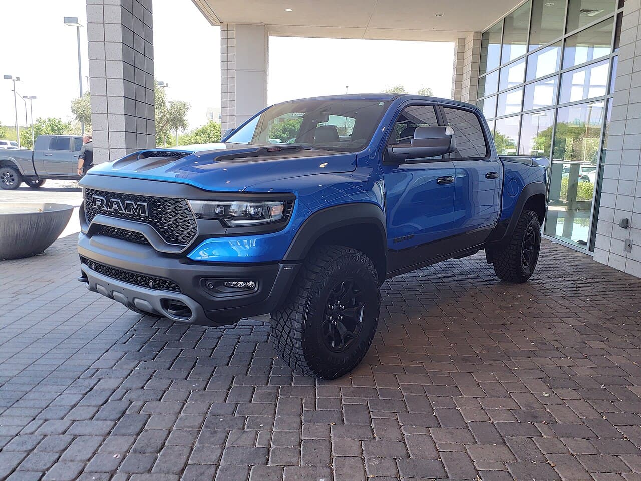 Front three-quarter view of a blue Ram 1500 TRX parked under a dealership canopy in Gilbert, Arizona.