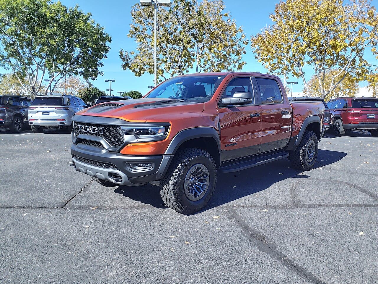 Front three-quarter view of a copper/orange 2024 Ram 1500 TRX Final Edition in a dealership parking lot.