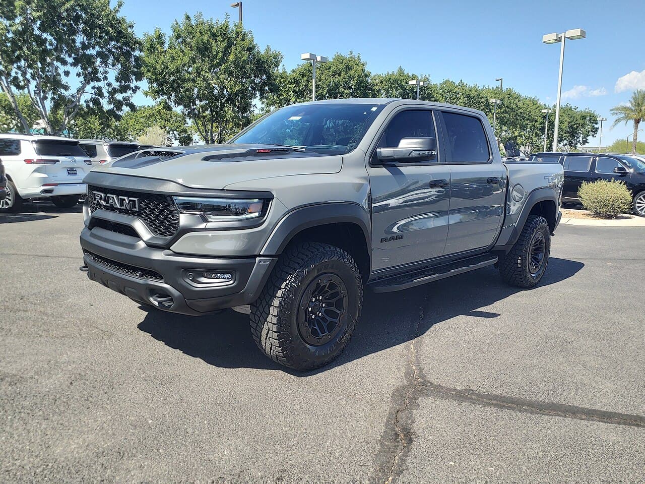Front three-quarter view of a gray Ram 1500 TRX in a dealership parking lot in Gilbert, Arizona.