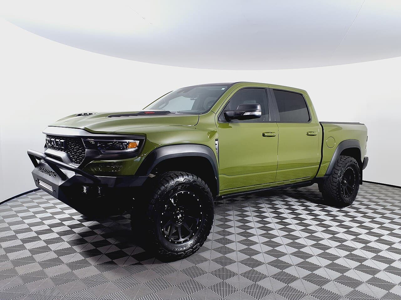 Front three-quarter studio shot of an olive-green Ram 1500 TRX modified into a Hennessey Mammoth 1000 with an aftermarket front bumper and wheels.