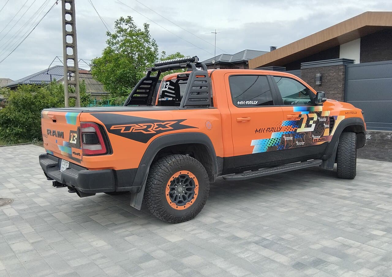 Rear three-quarter view of an orange Ram 1500 TRX in a rally-style livery (MK RALLY, car number 13) with a roll cage and light bar, parked in a residential driveway in Rostov-on-Don, Russia (file is mistitled generically on Commons but the truck is a TRX).
