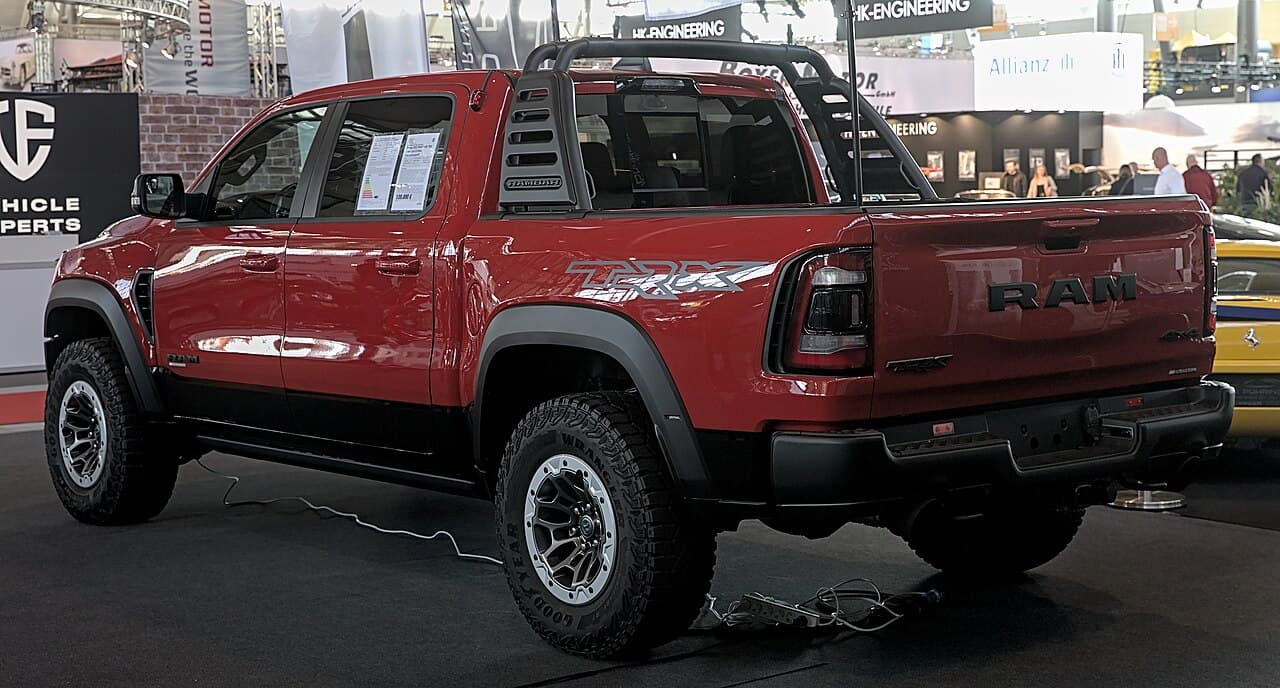 Rear three-quarter view of the same red Ram 1500 TRX at Retro Classics 2022, fitted with a roll bar and showing a 'TRX' decal on the bed side.